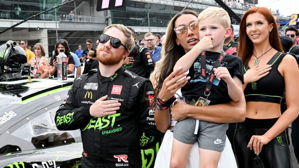 NASCAR Cup Series driver Tyler Reddick (45) stands with his wife, Alexa De Leon, and son, Beau, during the national anthem ahead of the Brickyard 400, Sunday, July 21, 2024, at Indianapolis Motor Speedway.