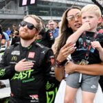NASCAR Cup Series driver Tyler Reddick (45) stands with his wife, Alexa De Leon, and son, Beau, during the national anthem ahead of the Brickyard 400, Sunday, July 21, 2024, at Indianapolis Motor Speedway.