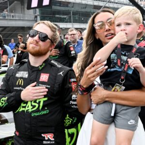 NASCAR Cup Series driver Tyler Reddick (45) stands with his wife, Alexa De Leon, and son, Beau, during the national anthem ahead of the Brickyard 400, Sunday, July 21, 2024, at Indianapolis Motor Speedway.