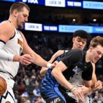 Dallas Mavericks forward Cooper Flagg (32) is fouled by Denver Nuggets forward Spencer Jones (21) as center Nikola Jokic (15) looks on during the second half at the American Airlines Center.
