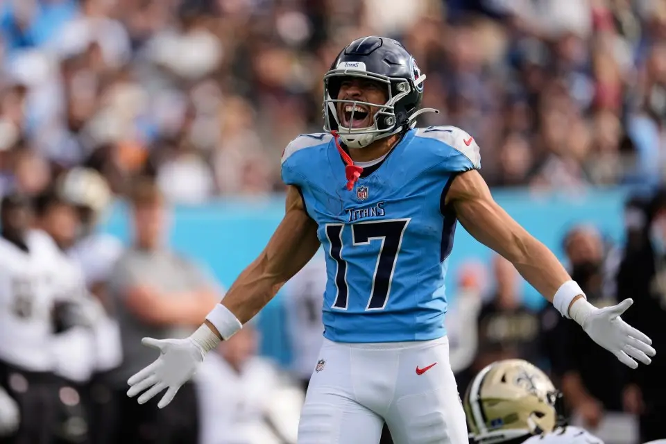 Football player celebrating in a blue Tennessee Titans jersey with vibrant crowd background.