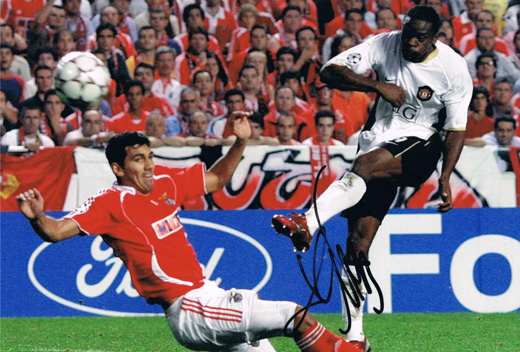 Louis Saha scoring a goal against Benfica in a UEFA Champions League match.