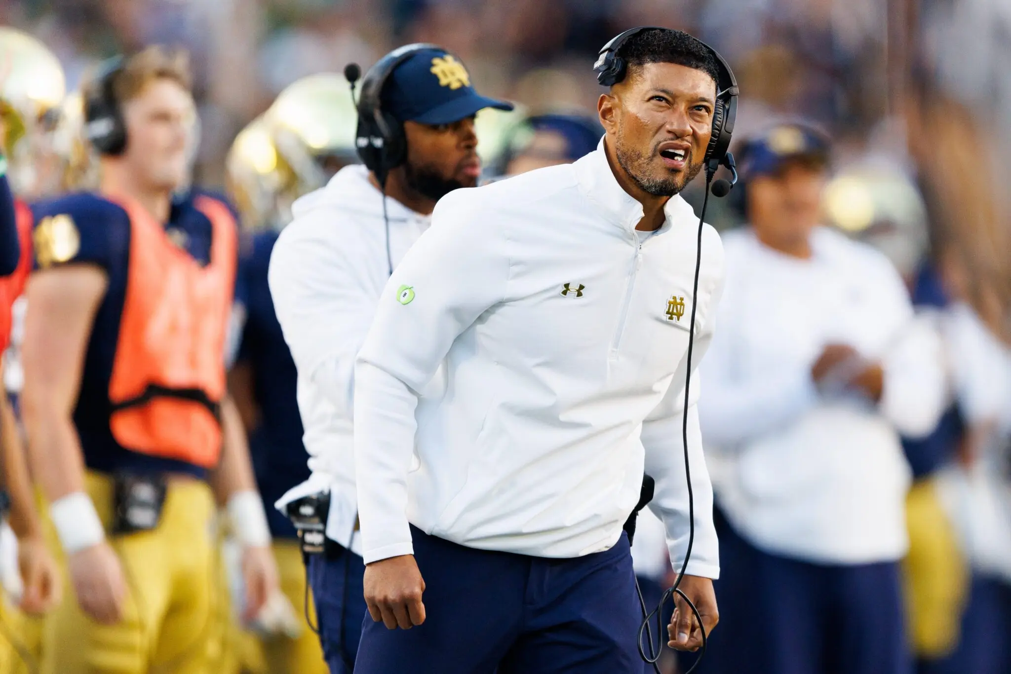 Marcus Freeman coaching during a Notre Dame football game, focused and energetic.