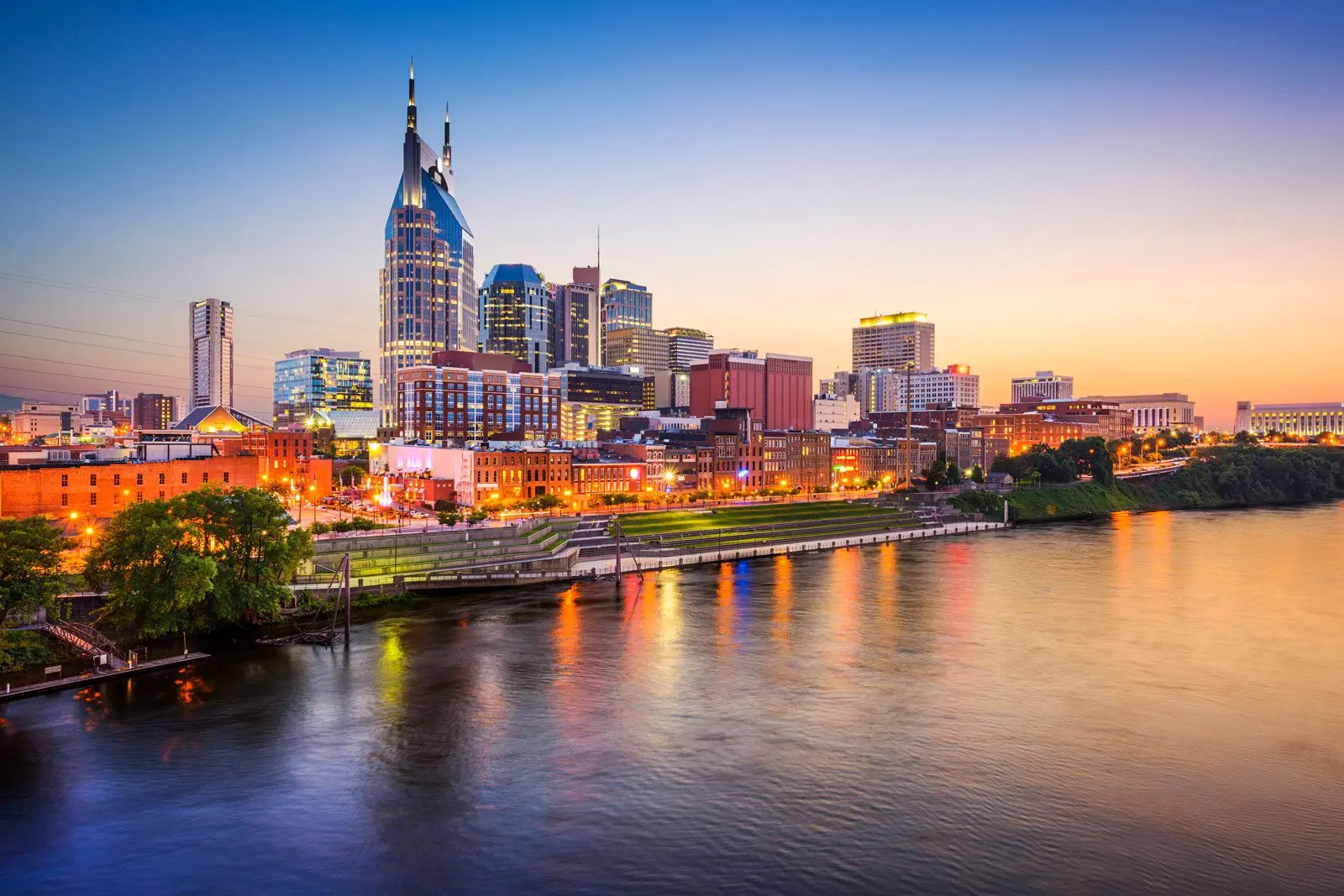 Nashville skyline at sunset with the Cumberland River in the foreground.