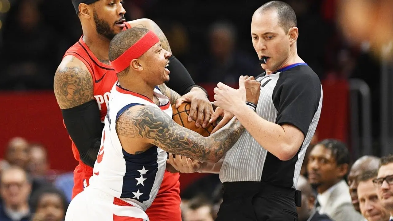 NBA player arguing with referee during a game with a crowd in the background.