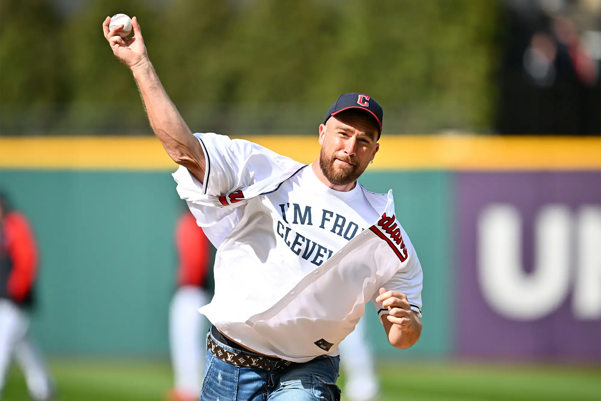 A man wearing a Cleveland baseball jersey throws a baseball.