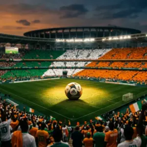 Floodlit stadium at golden hour with orange and green colour blocks, football on pitch under spotlight.