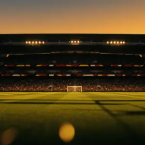 Floodlit football stadium at dusk with packed stands, dramatic shadow patterns, and golden-hour pitch lighting before kickoff.