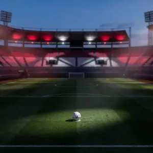 Floodlit stadium pitch under evening light with Paraguay national colours illuminating empty stands and a football on the centre spot.