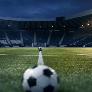 Floodlit football pitch with navy and white stadium lighting, geometric shadows on turf, single ball on centre spot.