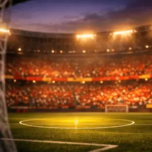 Floodlit stadium pitch in crimson and gold light with billowing goal net and empty centre circle, suggesting Spain's World Cup tournament readiness.