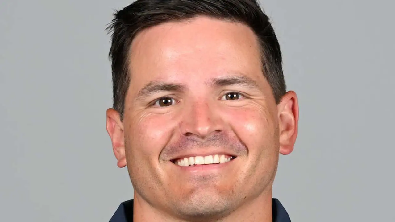 Headshot of Mike Macdonald smiling against a gray background