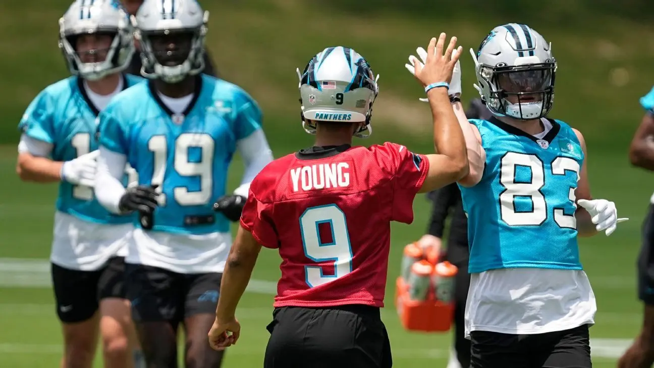 Bryce Young in a red Panthers jersey high-fiving a teammate in a blue jersey during practice.