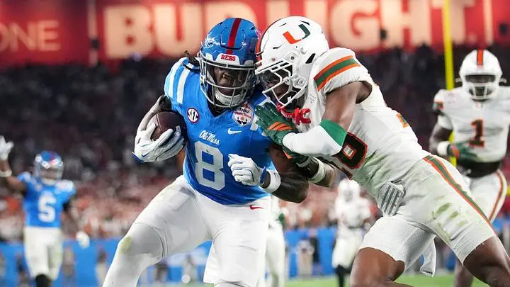 Ole Miss football player number 8 carrying the ball while being tackled by a Miami Hurricanes defender