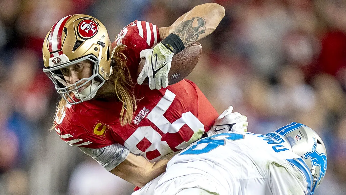 George Kittle of the San Francisco 49ers carrying a football while being tackled by a Detroit Lions player