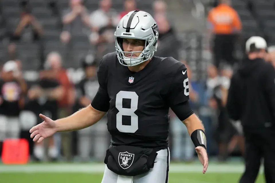 Kirk Cousins wearing a Las Vegas Raiders jersey and helmet on the football field