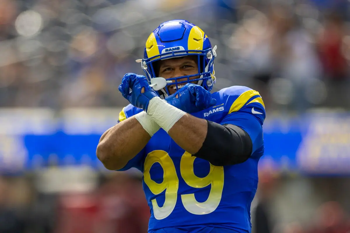 Aaron Donald of the Los Angeles Rams wearing a blue jersey with number 99 and a helmet, crossing his arms.