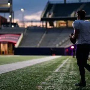 Quarterback silhouette holding a football during a late NFL trade and roster transition
